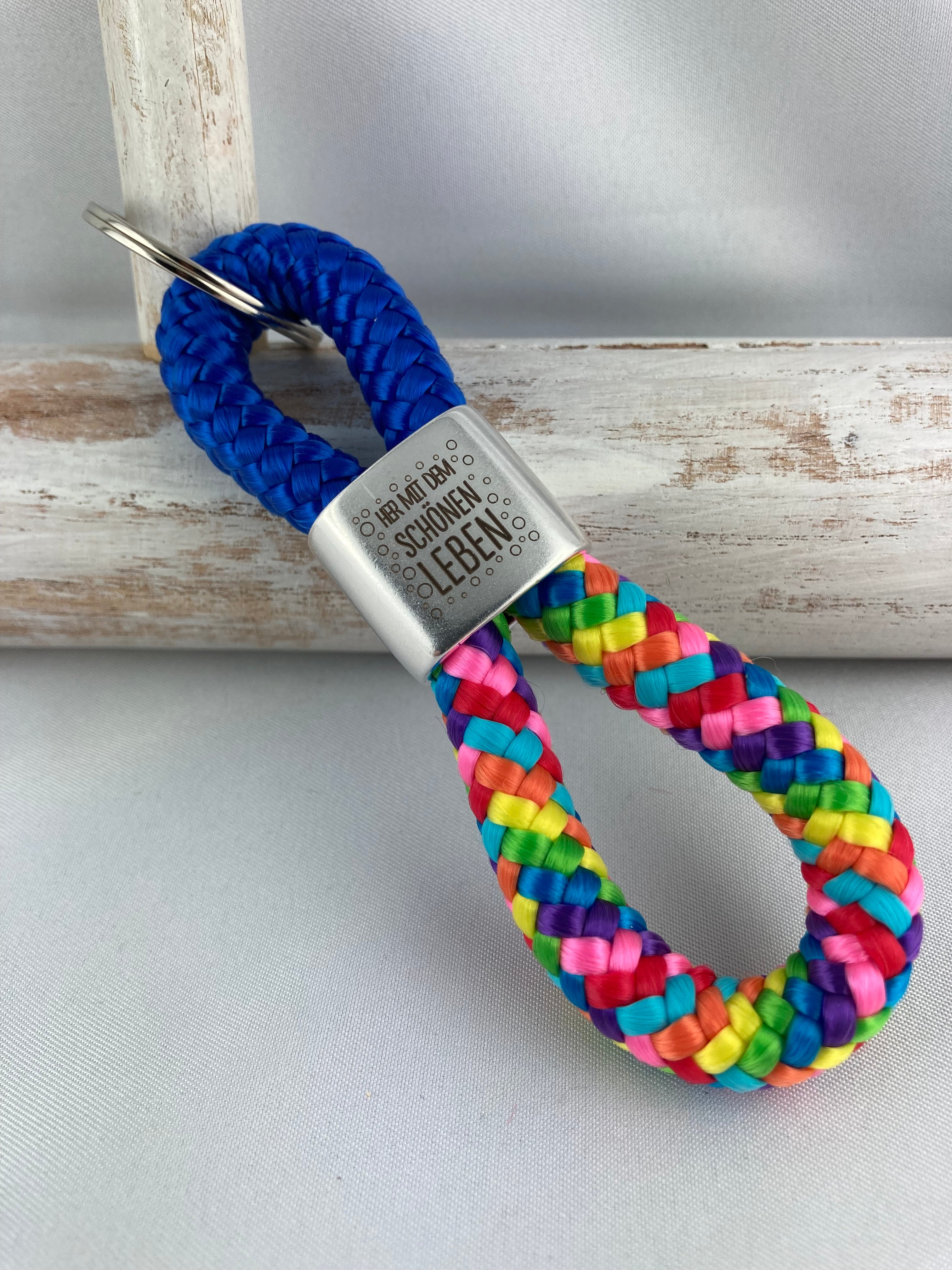 Schlüsselanhänger aus Segelseil mit versilbertem Zwischenstück mit Gravur "Her mit dem schönen Leben", blau/ regenbogen-mix