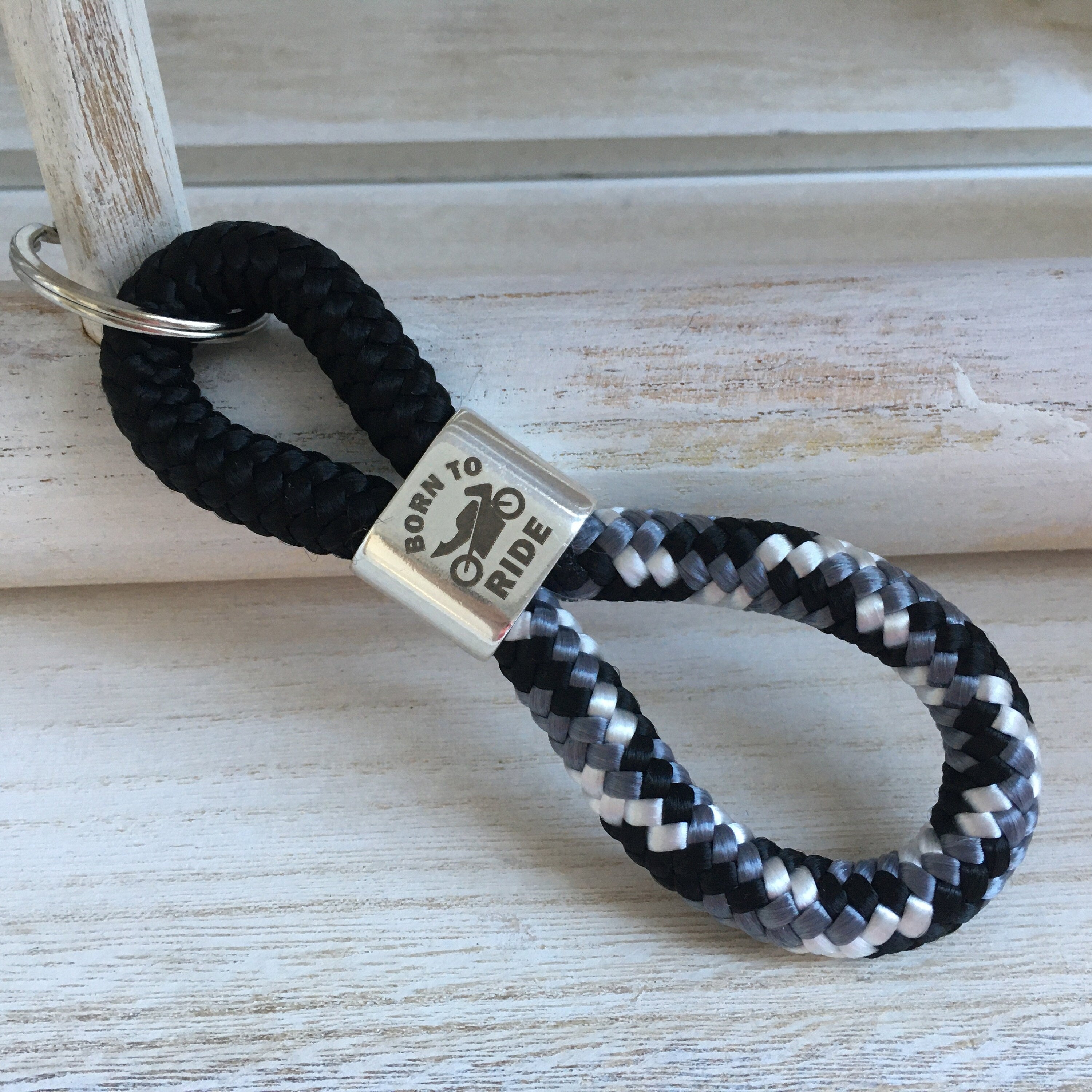 Schlüsselanhänger aus Segelseil mit versilbertem Zwischenstück mit Gravur "Born to ride", schwarz/ schwarz-weiß-grau