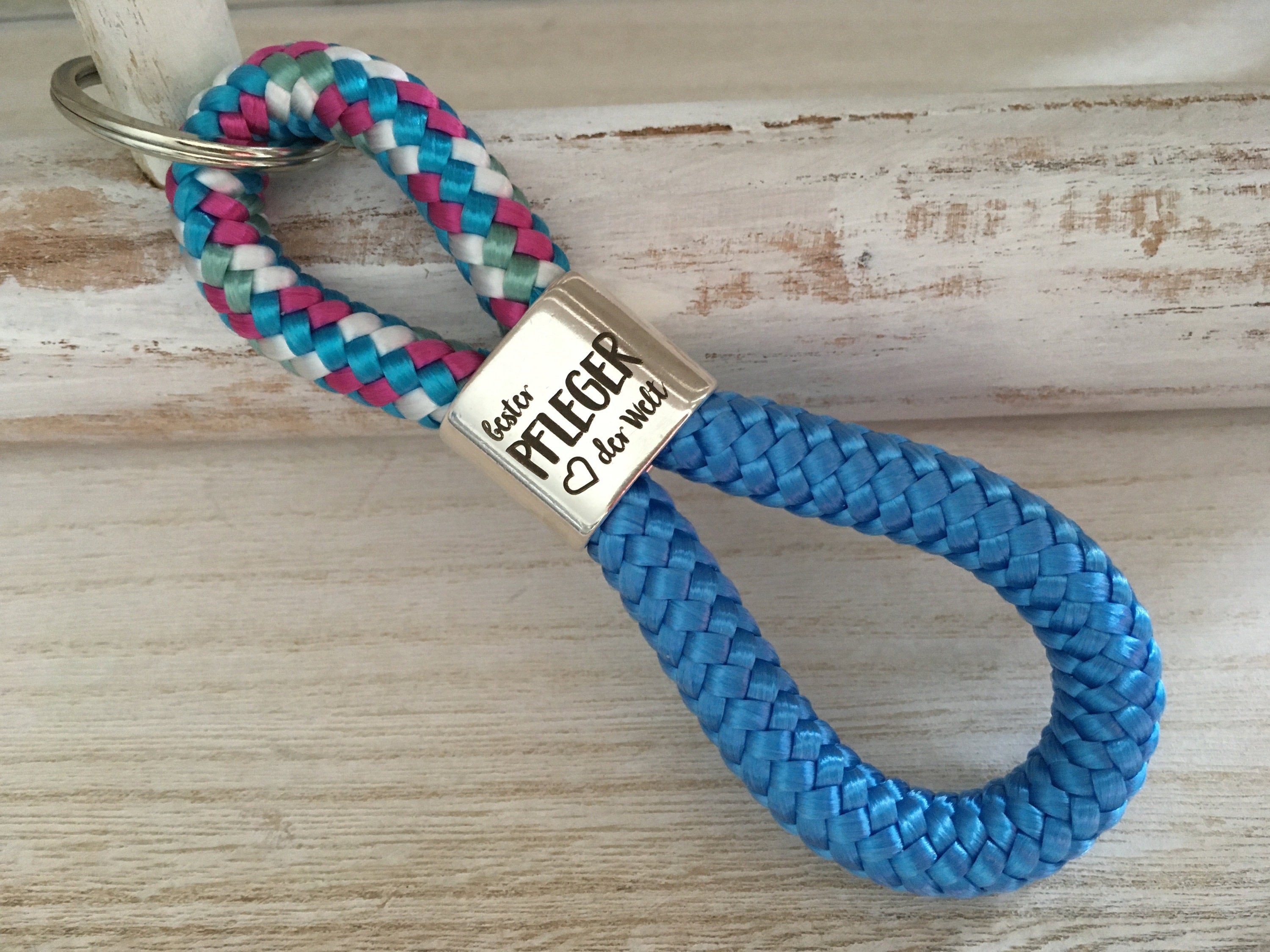 Schlüsselanhänger aus Segelseil mit versilbertem Zwischenstück mit Gravur "Bester Pfleger der Welt" weiß-blau-fuchsia-mix/himmelblau
