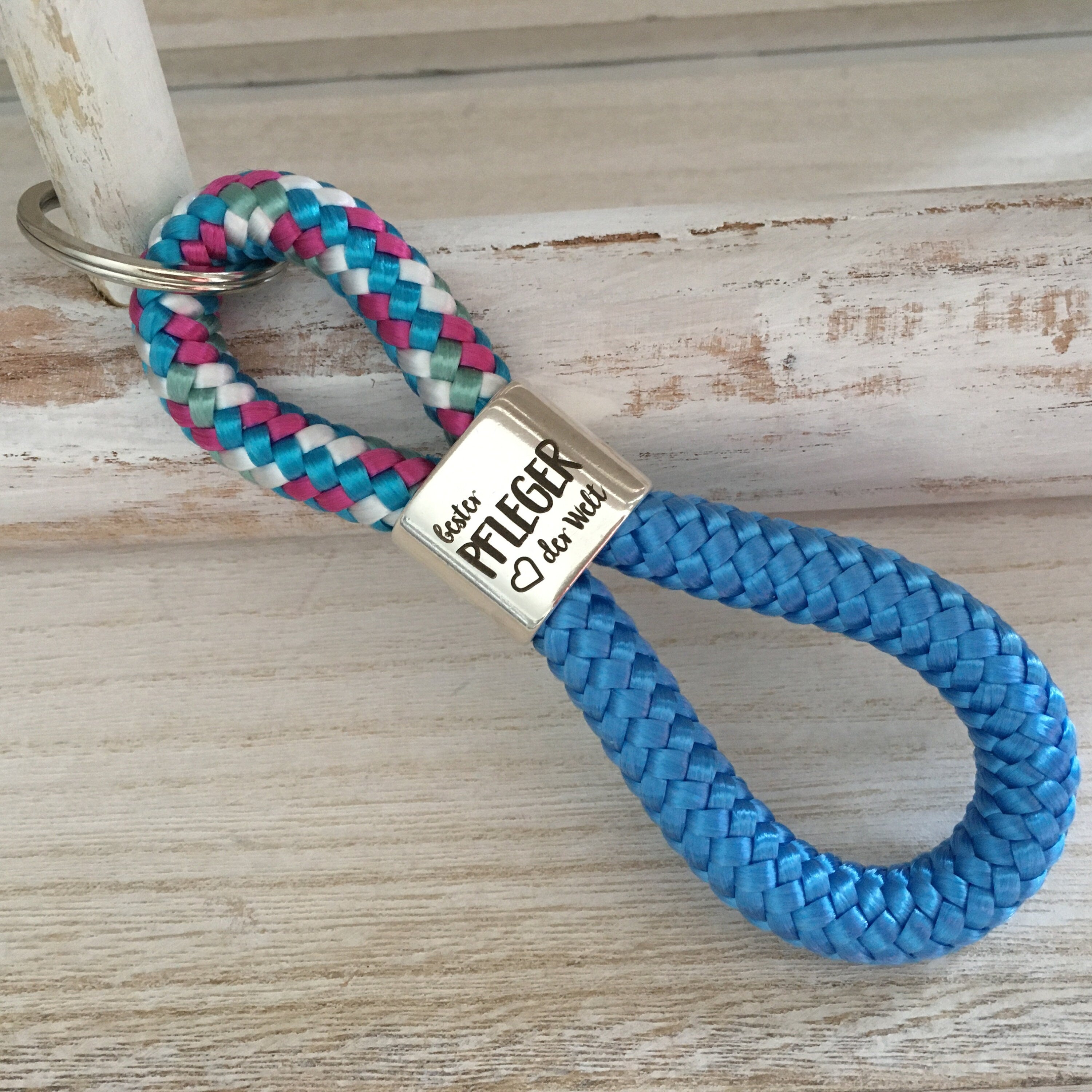 Schlüsselanhänger aus Segelseil mit versilbertem Zwischenstück mit Gravur "Bester Pfleger der Welt" weiß-blau-fuchsia-mix/himmelblau