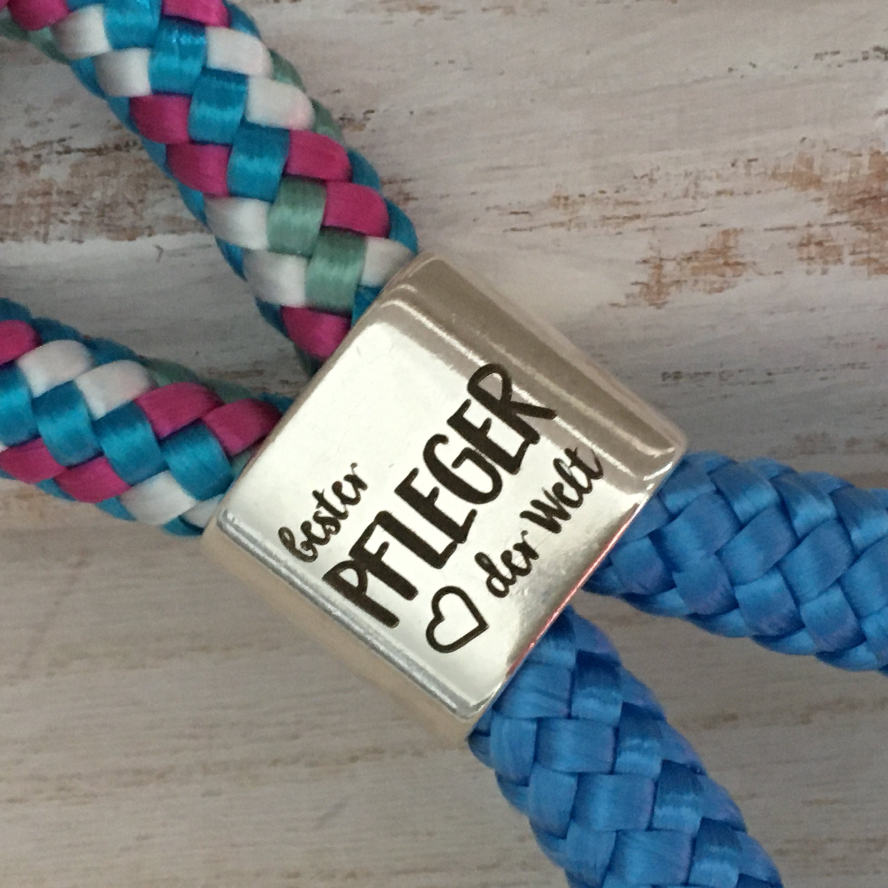 Schlüsselanhänger aus Segelseil mit versilbertem Zwischenstück mit Gravur "Bester Pfleger der Welt" weiß-blau-fuchsia-mix/himmelblau