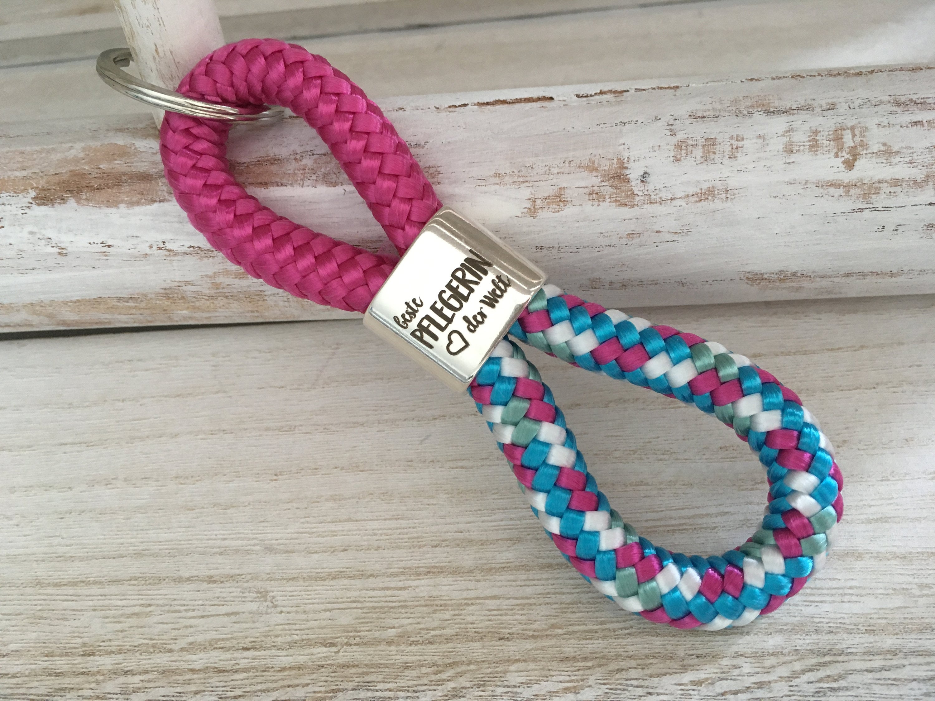 Schlüsselanhänger aus Segelseil mit versilbertem Zwischenstück mit Gravur "Beste Pflegerin der Welt" fuchsia/ weiß-blau-fuchsia-mix