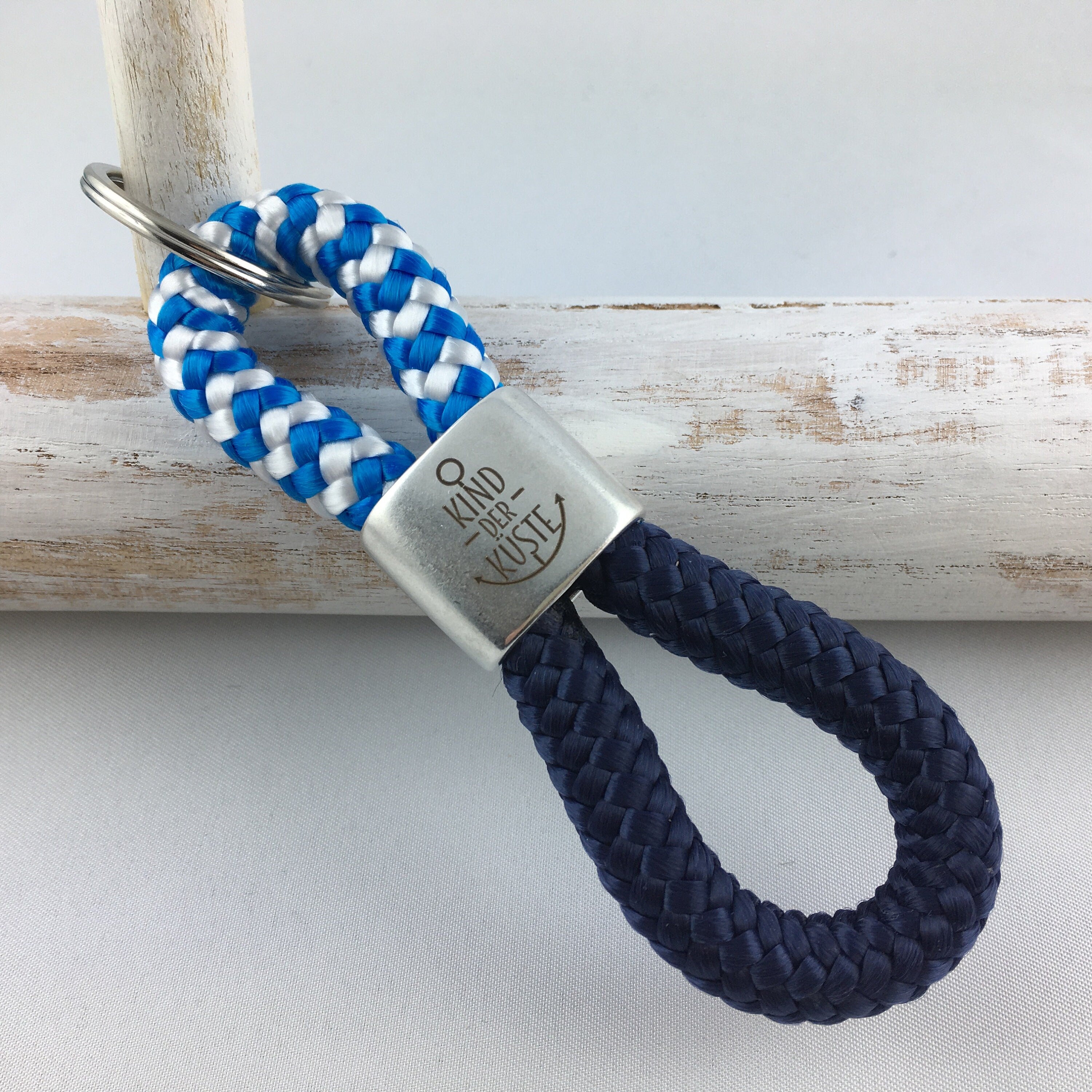 Schlüsselanhänger aus Segelseil mit versilbertem Zwischenstück mit Gravur "Kind der Küste" blau-weiß/ dunkelblau