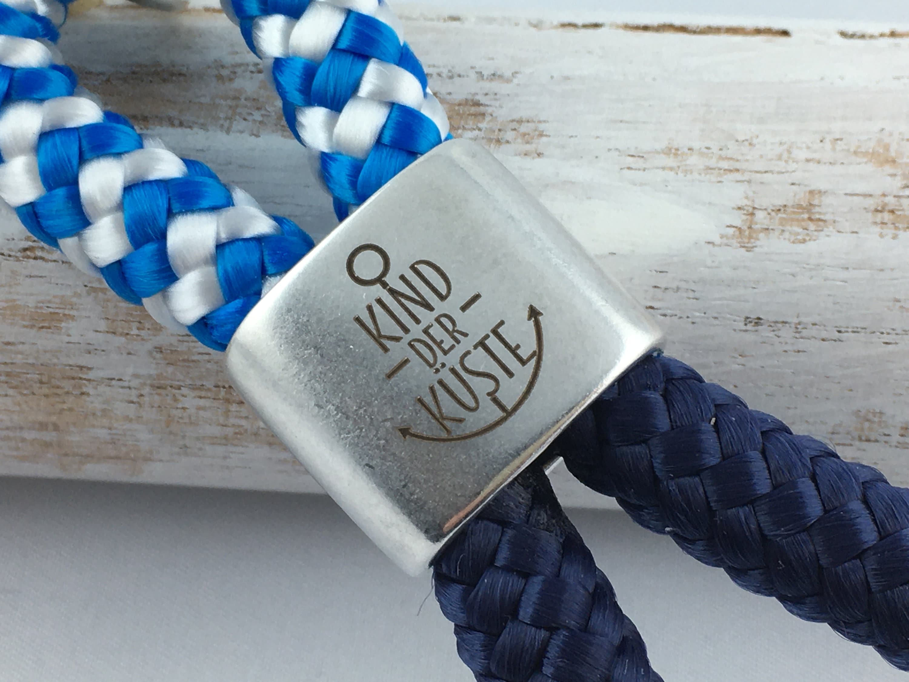 Schlüsselanhänger aus Segelseil mit versilbertem Zwischenstück mit Gravur "Kind der Küste" blau-weiß/ dunkelblau