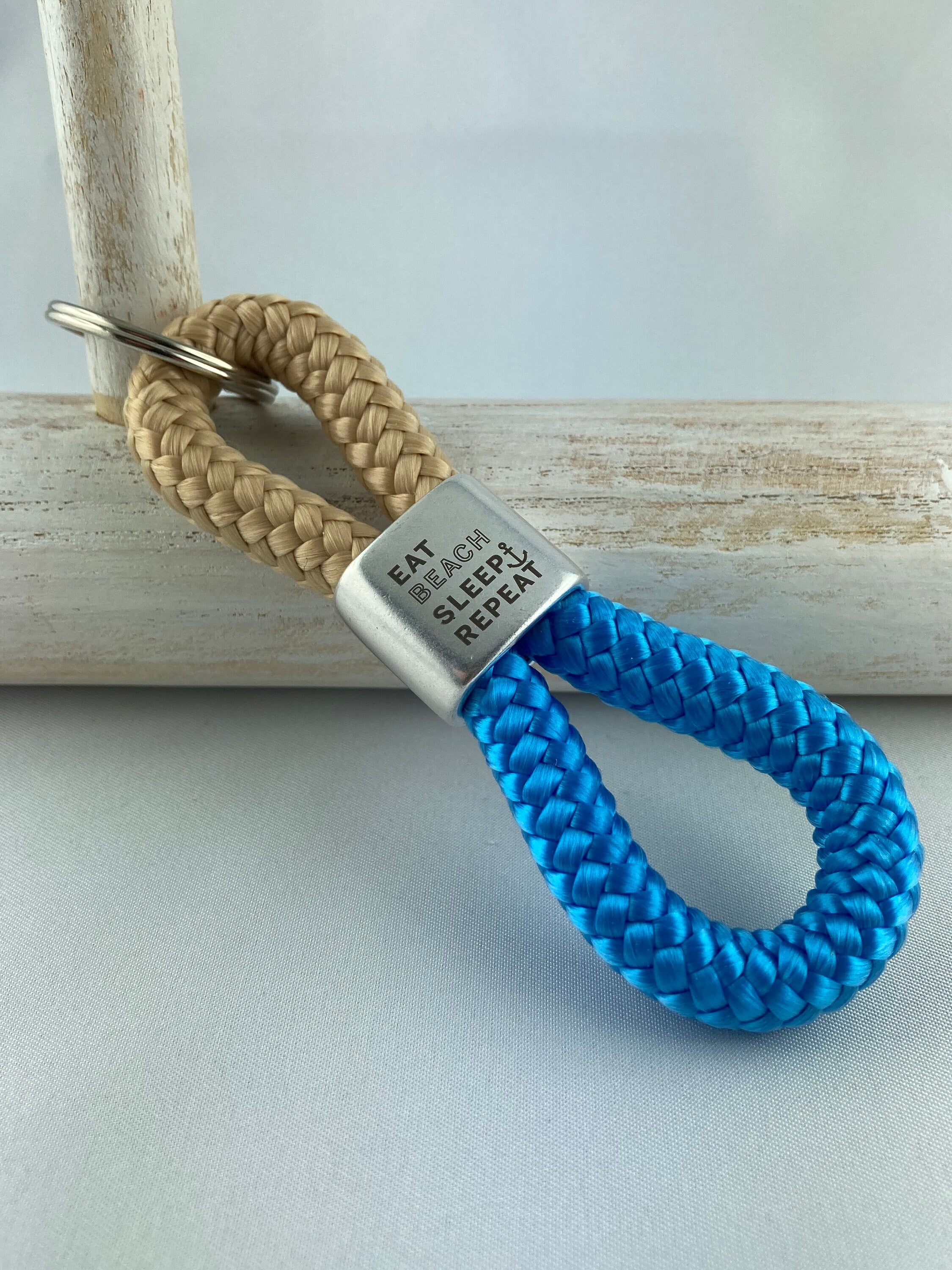 Schlüsselanhänger aus Segelseil mit versilbertem Zwischenstück mit Gravur "eat beach sleep repeat", beige/ himmelblau