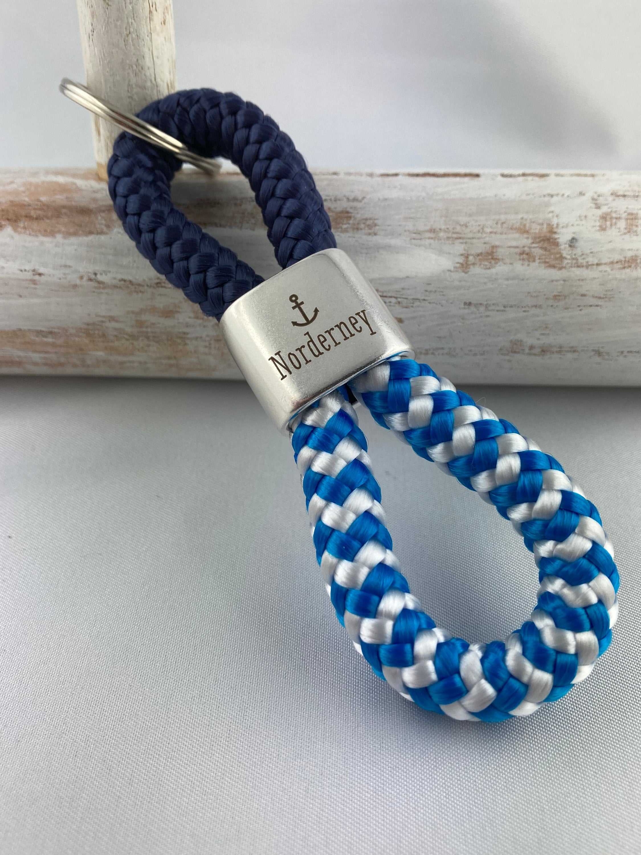 Schlüsselanhänger aus Segelseil mit versilbertem Zwischenstück mit Gravur "Norderney", dunkelblau/ blau-weiß