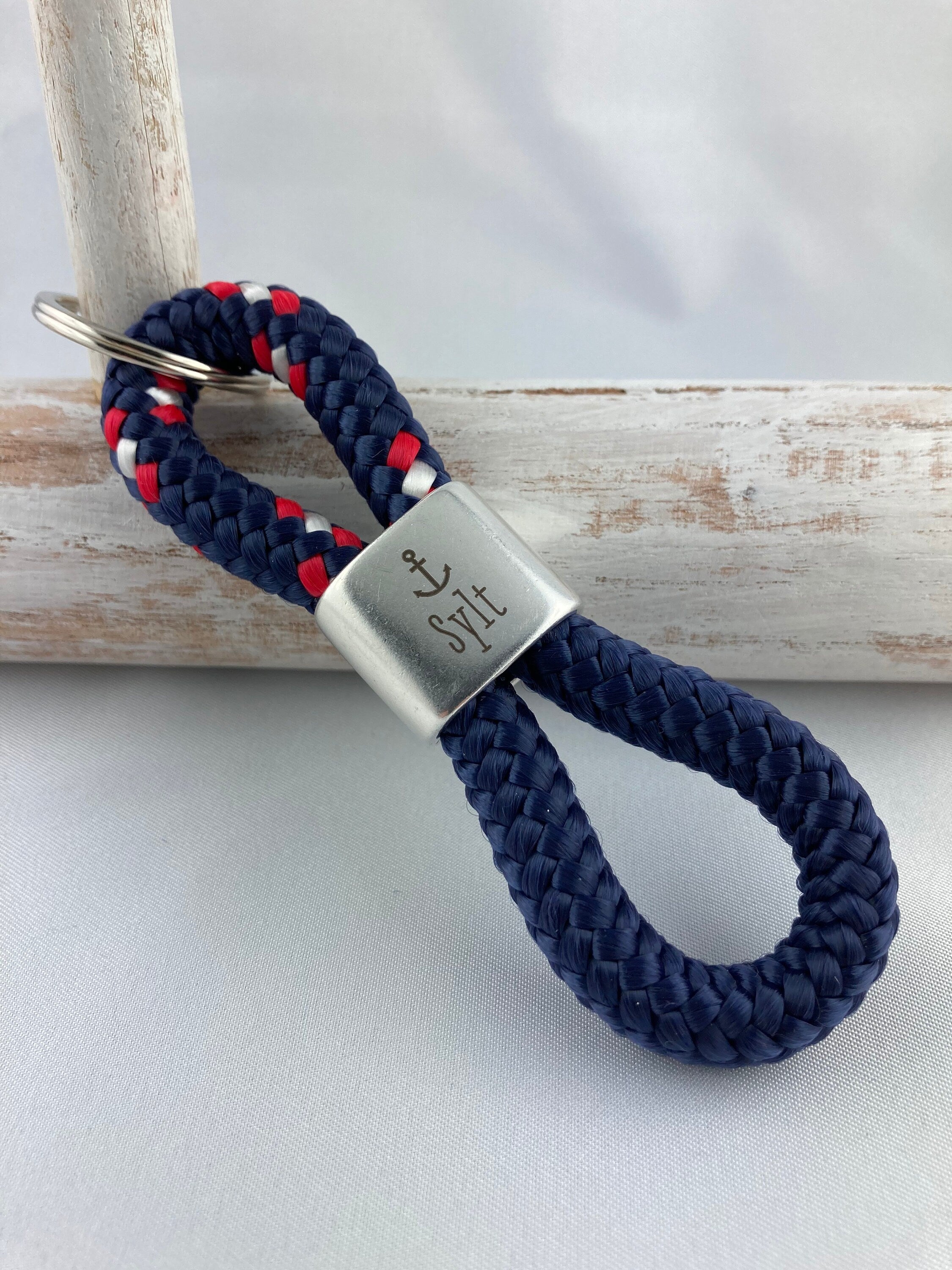 Schlüsselanhänger aus Segelseil mit versilbertem Zwischenstück mit Gravur "Sylt", blau-rot-weiß/ dunkelblau