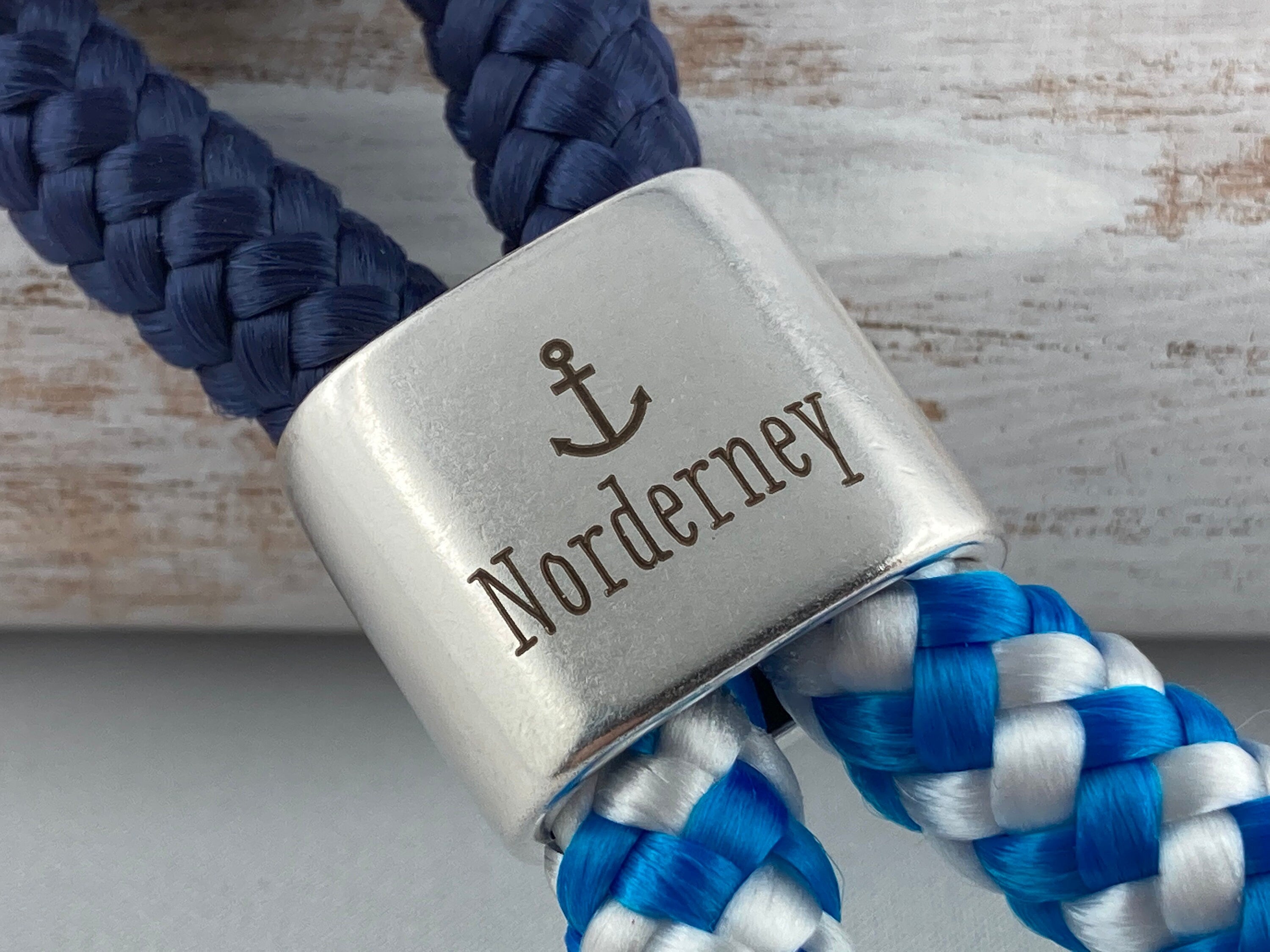 Schlüsselanhänger aus Segelseil mit versilbertem Zwischenstück mit Gravur "Norderney", dunkelblau/ blau-weiß