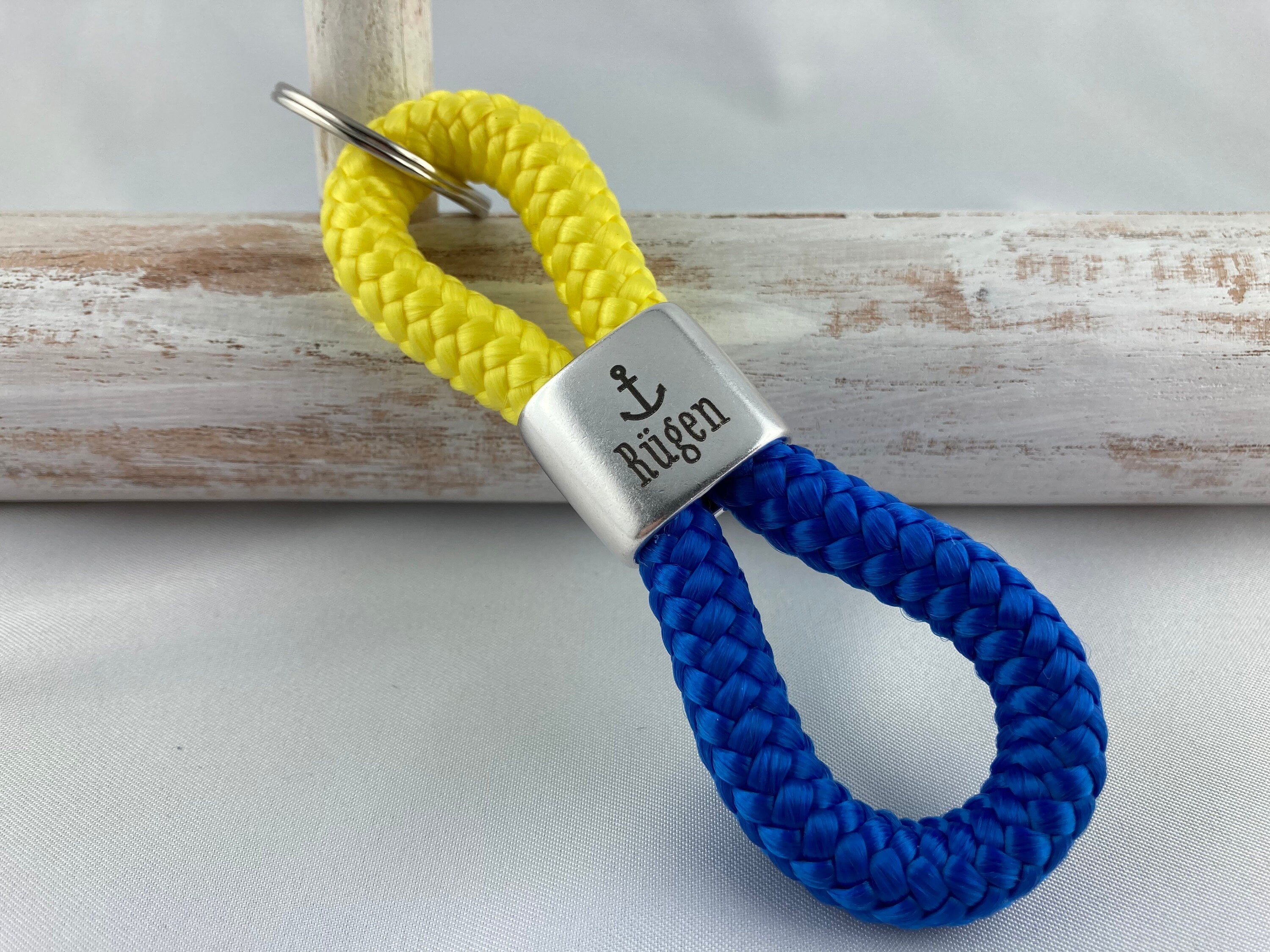 Schlüsselanhänger aus Segelseil mit versilbertem Zwischenstück mit Gravur "Rügen", gelb/ blau