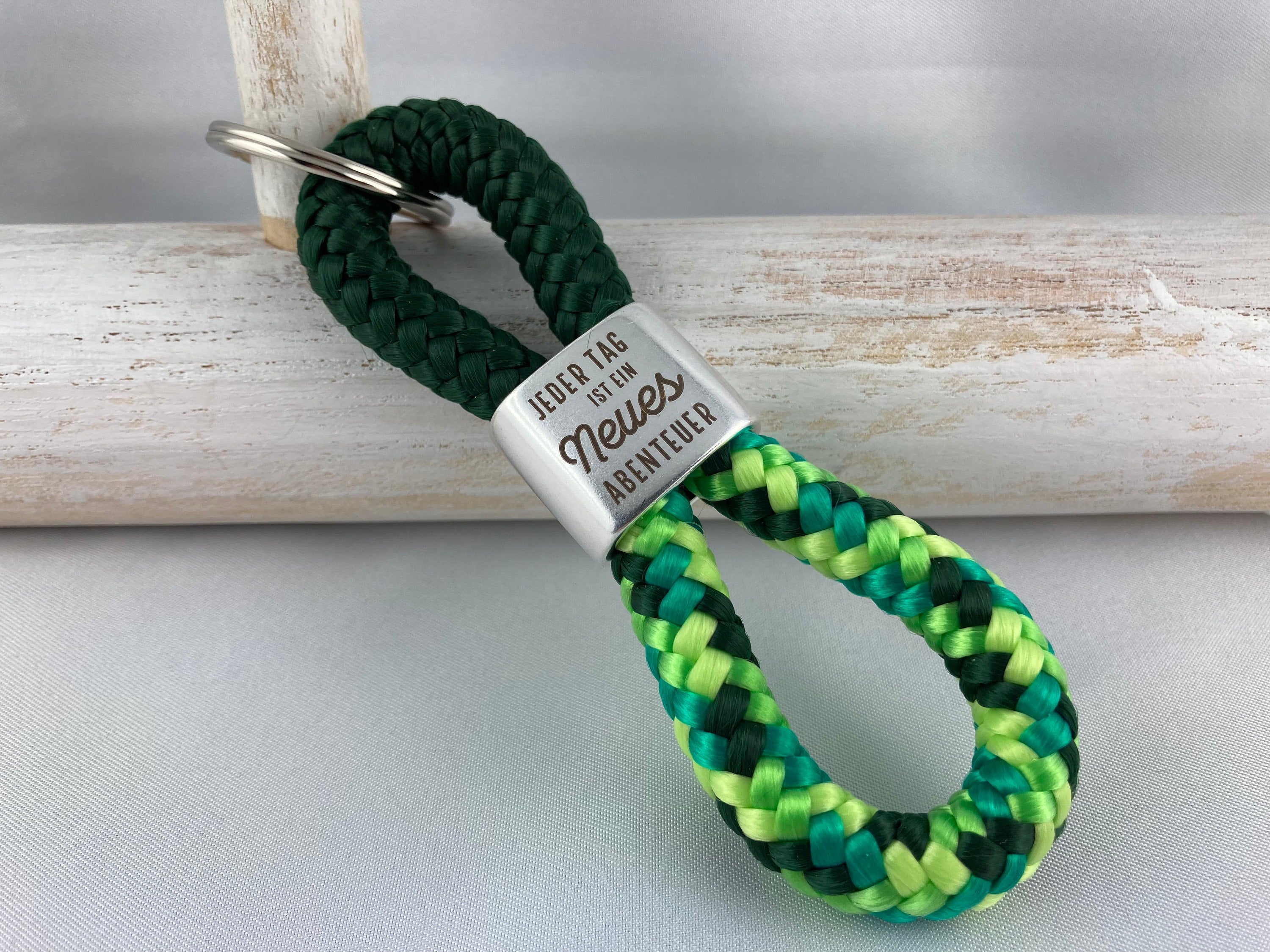 Schlüsselanhänger aus Segelseil mit versilbertem Zwischenstück mit Gravur "Jeder Tag ist ein neues Abenteuer", dunkelgrün/ grün-mix