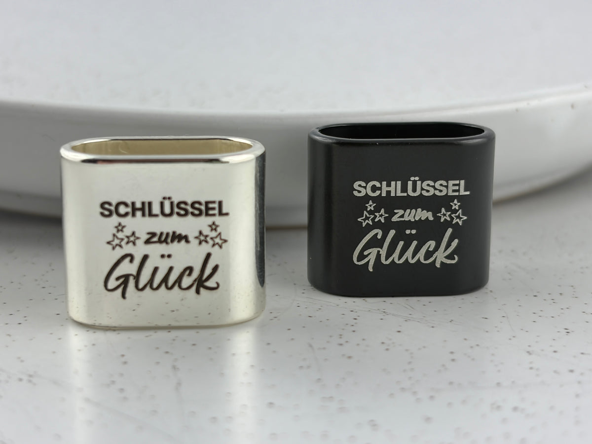 Detailaufnahme der Gravur "Schlüssel zum Glück" mit kleinen Sternen auf dem Zwischenstück