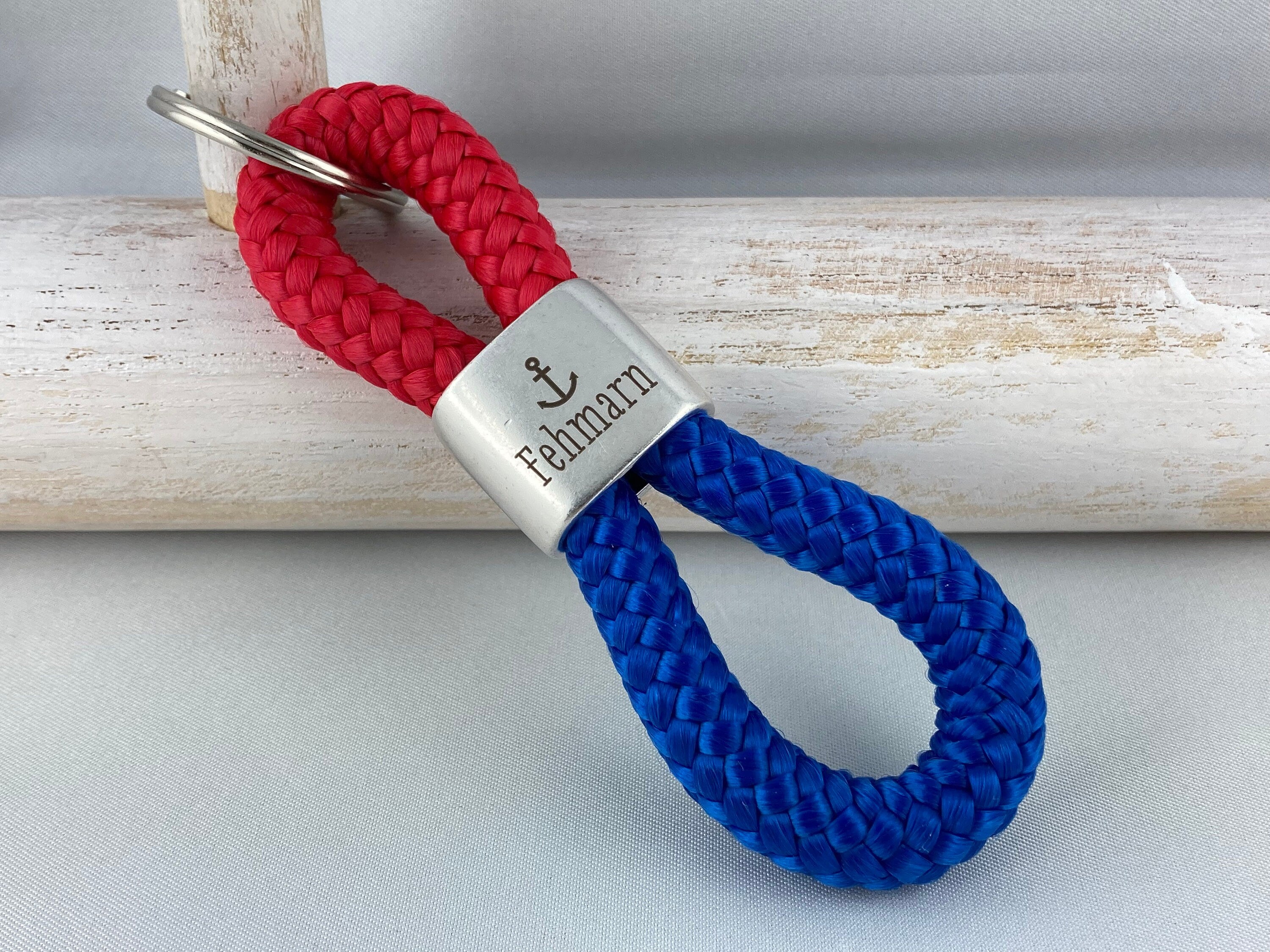 Schlüsselanhänger aus Segelseil mit versilbertem Zwischenstück mit Gravur "Fehmarn", rot/ blau